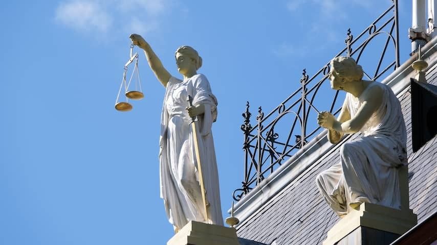 Image of Lady Justitia on the facade of the former courthouse on the Noordsingel in Rotterdam. Next to her a kneeling plumbling.